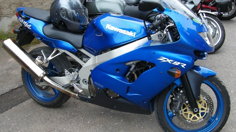 A metallic blue Kawasaki Ninja ZX-9R motorcycle with matching blue wheels parked outdoors.