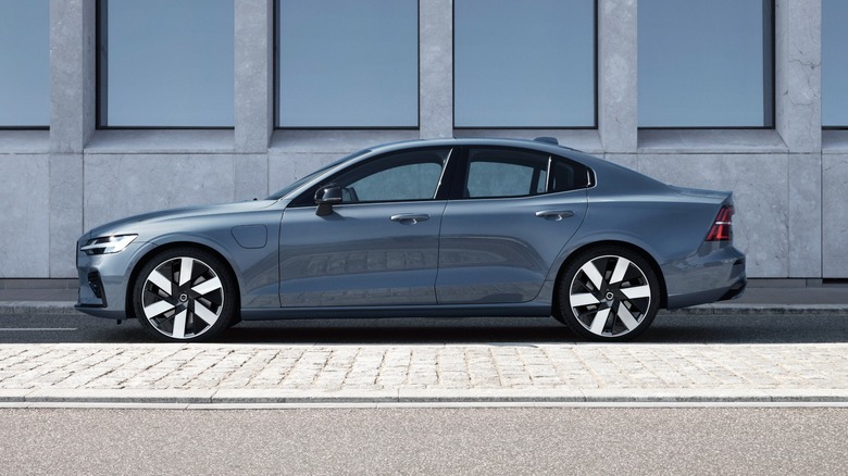 A grey Volvo S60 Recharge parked by the side of a building