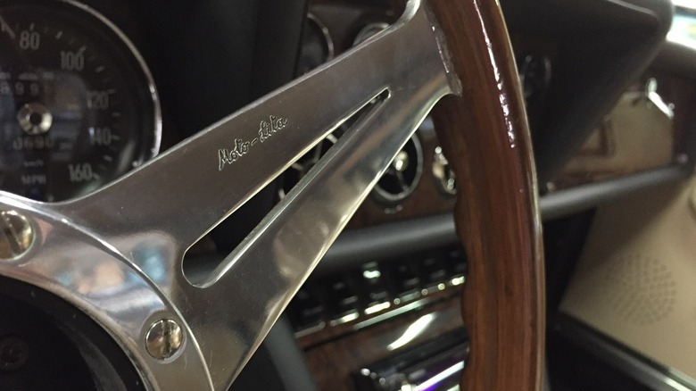 A close-up of a "Moto-Lita"-etched (and made) steering wheel, metal insert with wooden rim, in an old Jaguar.