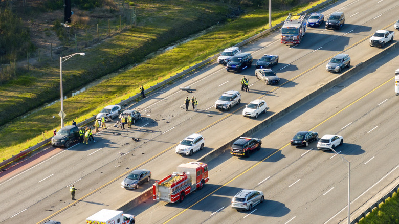 An aerial view of a scene of a highway accident with first responders and debris on the road