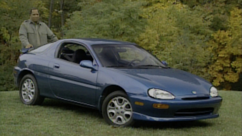 A blue 1992 Mazda MX-3 parked on a green lawn
