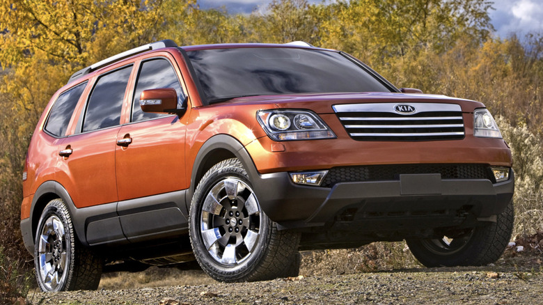 Kia Borrego parked on gravel with trees in the background