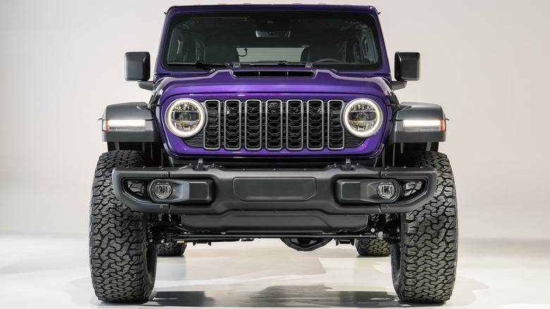 A head-on shot of a purple Jeep Wrangler 392 parked in an all white studio with its DRLs on