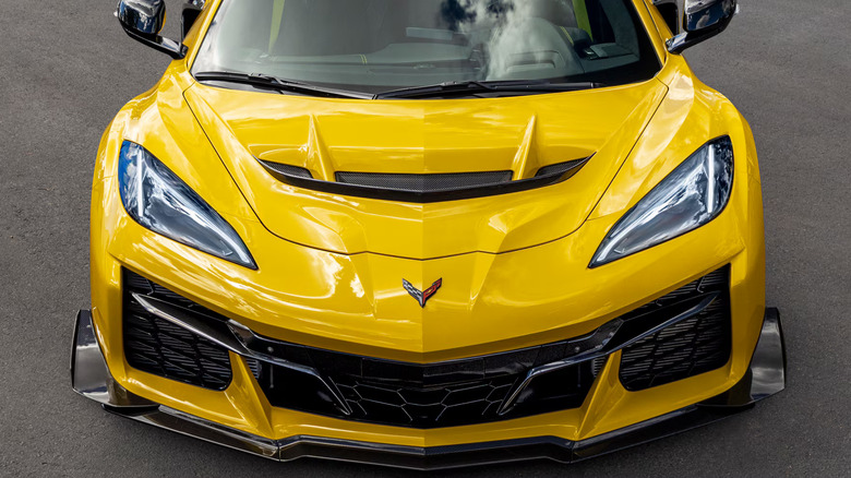 A yellow C8 Corvette ZR1, highlighting its aggressive carbon-fiber nose splitter and massive flow-through S-duct hood vent.