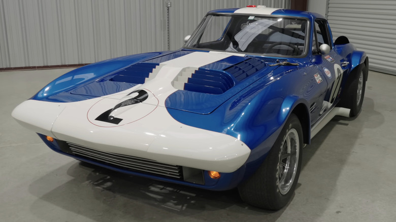 A classic blue and white 1963 C2 Corvette Grand Sport race car with the racing number 2 on its white nose, parked in a garage.