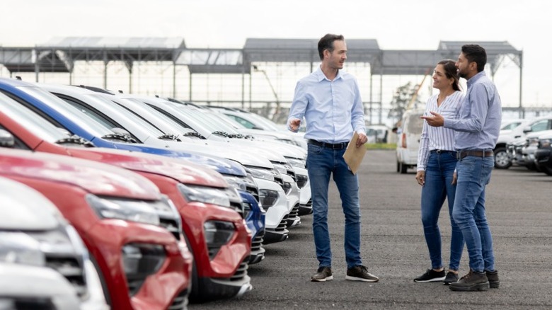 A salesperson showing cars to couple