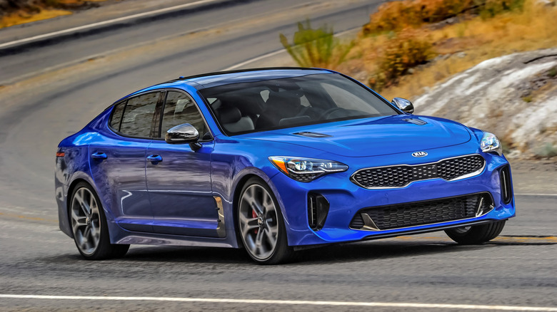A blue 2021 Kia Stinger GT2 rounds a curve.