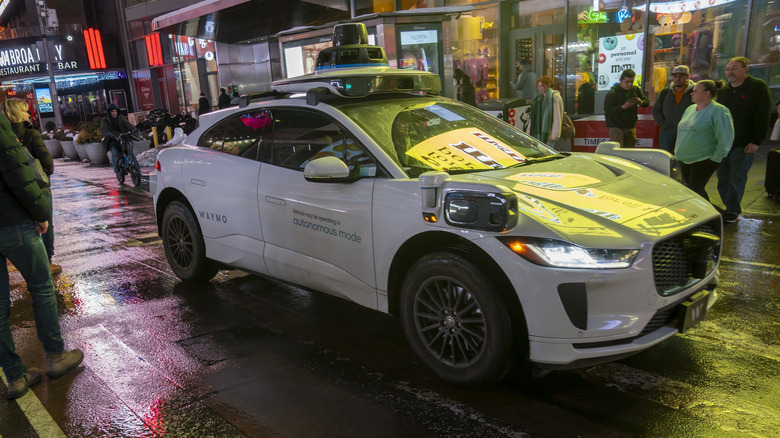 Waymo vehicle stopped with pedestrians walking around it