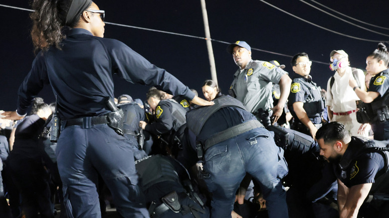 Several police and federal agents tackle and arrest a person