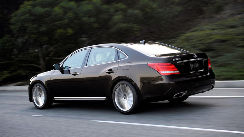 A rear 3/4 view of a black 2015 Hyundai Equus driving down a road