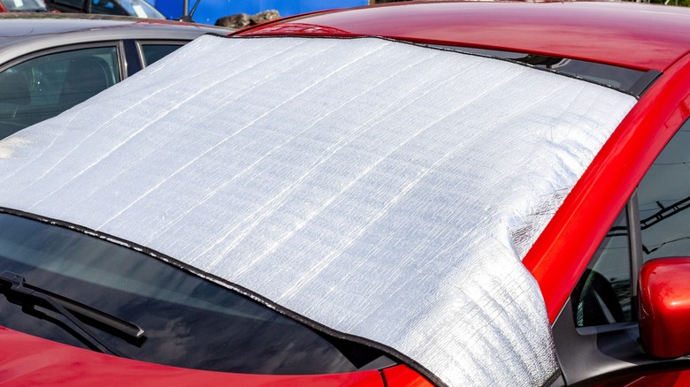 A reflective sunshade anchored inside the dashboard of a car.