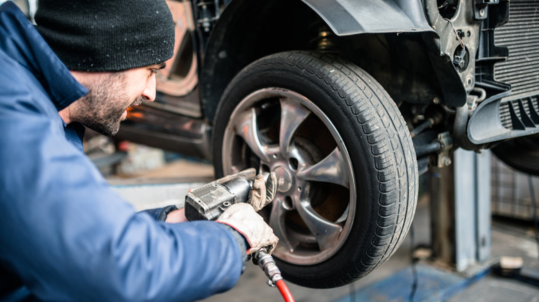 A mechanic mounting a wheel on a car.