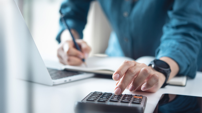 A man uses a calculator at a desk.