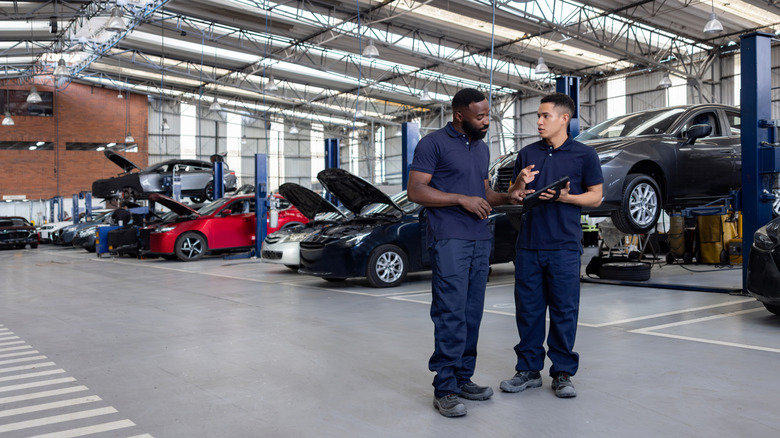 Two men speak in an automotive service bay.