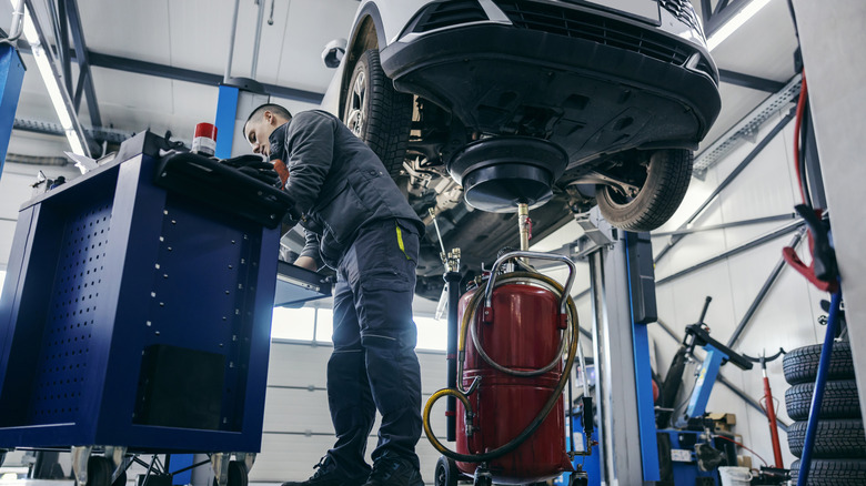 A mechanic changing the oil on a car.